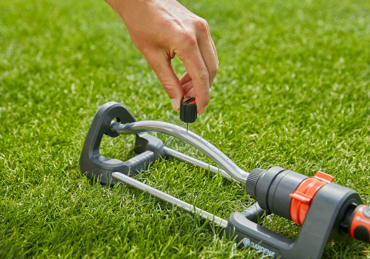 Sproeikoppen schoon te maken met naald in de schroefdop