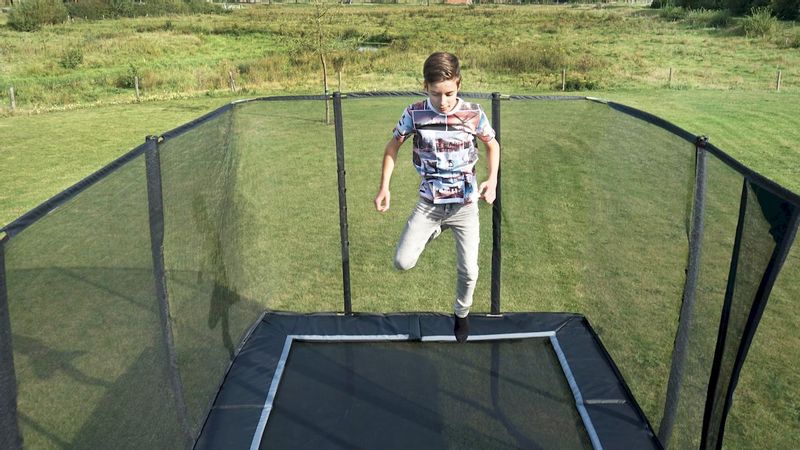 Exit PeakPro trampoline met net en ladder - 458 x 275 cm - Zwart - met springende jongen